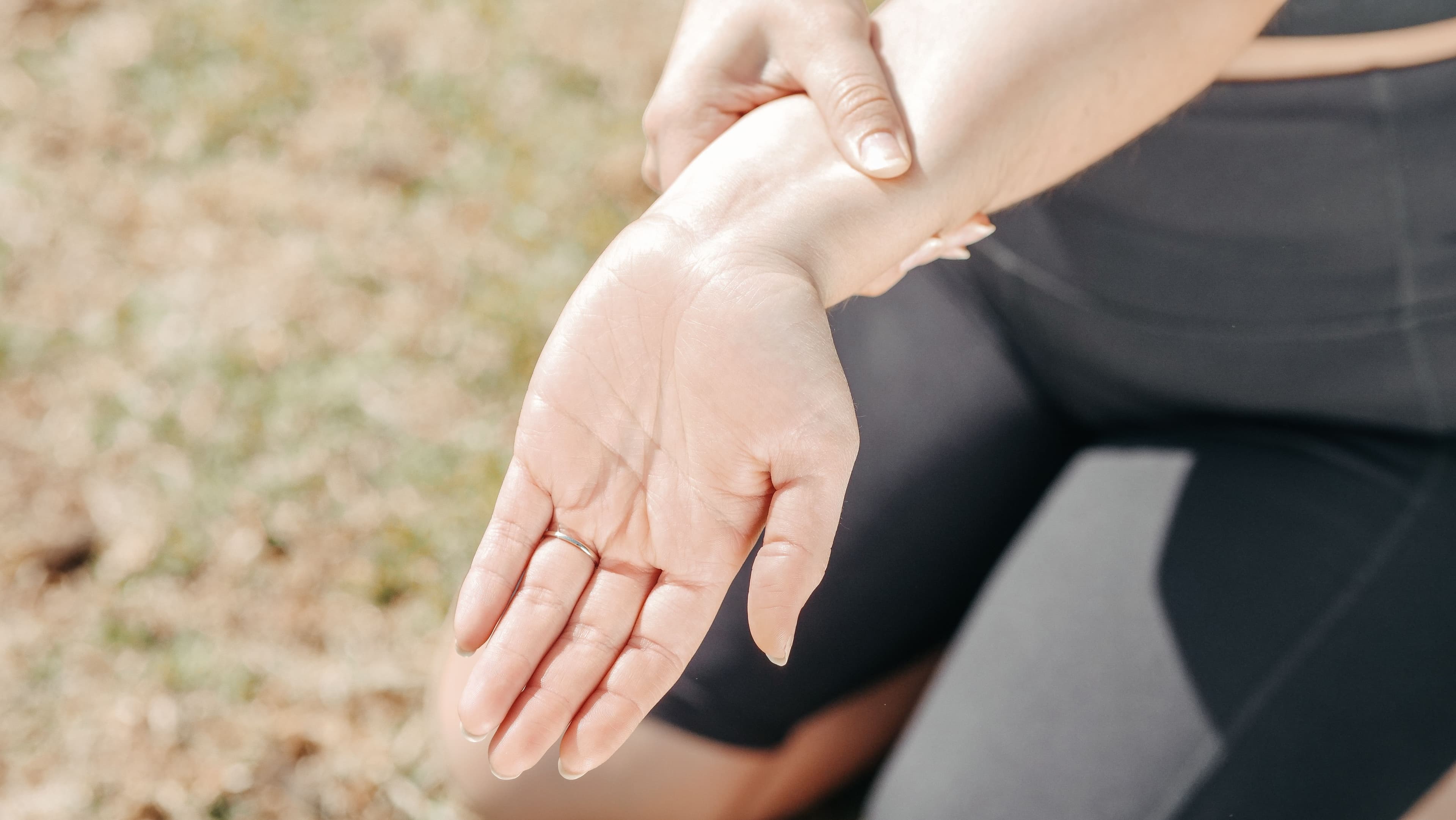 Persona sosteniéndose la muñeca por dolor articular, al aire libre